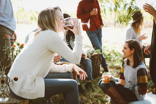 Amigos reunidos, homens e mulheres sentados no campo, conversando e bebendo.
A reunião com os amigos afasta os pensamentos negativos.