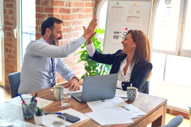 homem e mulher sorrindo e comemorando na mesa de trabalho